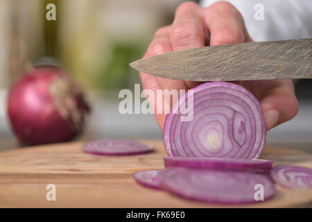 Koch, Hinzufügen von Würfeln Zwiebeln auf Tisch Stockfoto