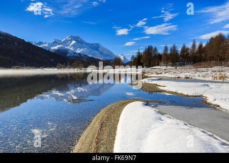 Schneebedeckte Gipfel spiegeln sich im Silvaplanasee noch teilweise gefroren, Maloja, Kanton Graubünden, Engadin, Schweiz, Europa Stockfoto