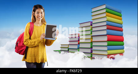 Zusammengesetztes Bild des Lächelns asiatische Studentin zeigt tablet Stockfoto