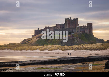 Zwei Menschen joggen vorbei Bamburgh Castle in Northumberland Küste, England Stockfoto