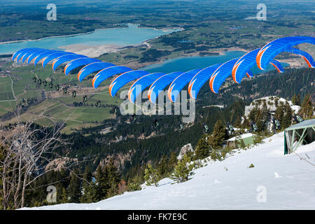 Füssen, Deutschland - 9. April 2015: blaue Gleitschirm Start vom Tegelberg über den Foggensee Stockfoto