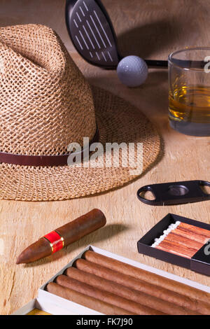 Siesta - Zigarre, Strohhut, Scotch Whisky und Golf-Fahrer auf einem Holztisch Stockfoto