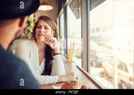 Schöne junge Frau in einem Café sitzen und mit Blick auf ihren Freund. Junges Paar im Coffee Shop. Stockfoto
