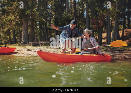 Porträt von reifer Mann mit einer Frau in einem Kajak im See. Mann, die Frau, die etwas interessantes zeigen Paddel. Senioren c Stockfoto