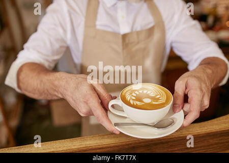 Nahaufnahme des Mannes in Schürze mit Kaffee im stehen in Coffee-Shop. Geben Sie eine Tasse frischen Kaffee im Café Barista. Stockfoto