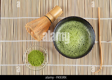 Grünen Matcha Tee mit Bubbles über Ansicht mit Schneebesen und Pulver und Löffel Stockfoto