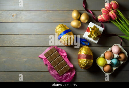 Gold Ostereier mit Frühling Tulpen und Geschenk-Box auf einem Holztisch Stockfoto