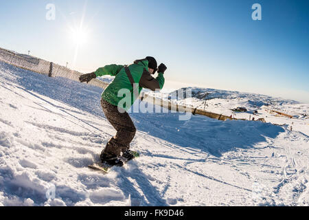 Snowboard-Freerider in den Bergen gegen Sonne am blauen Himmel. Stockfoto