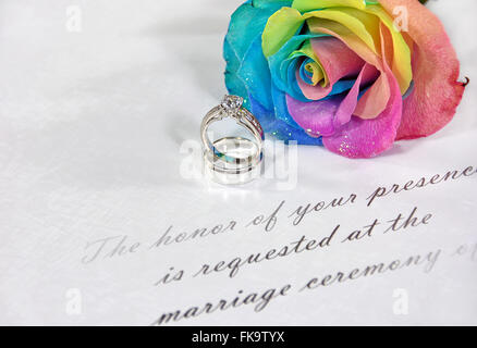 Trauringe und Regenbogen stieg auf traditionelle Hochzeitseinladung. Stockfoto