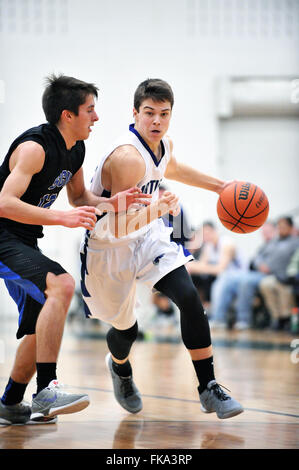 Player fahren auf den gegnerischen Korb, während sich eng an seine voraus während einer High School Basketball Spiel verteidigt zu werden. USA. Stockfoto