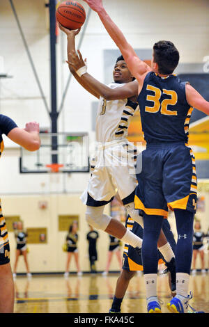 Nach einer Fahrt auf den Reifen ein Spieler gehen, um die Luft in einer scoring Anstrengung über einen Verteidiger bei einem High-School-Basketball-Spiel. Stockfoto