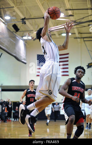 Nach einer Fahrt auf den Ring, mit dem ein Spieler sich an die Luft in einem Scoring Anstrengung über einen Verteidiger, während ein High School Basketball Spiel. USA. Stockfoto