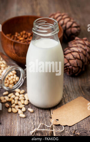 Zeder-Milch in eine Flasche, Pinienkernen und Tannenzapfen auf alten hölzernen Hintergrund Stockfoto