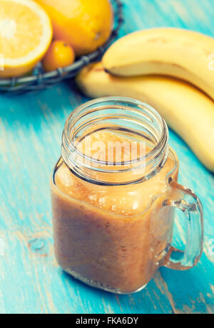 Smoothies mit Orangen und Bananen in einem Glas auf einem hölzernen Hintergrund Stockfoto