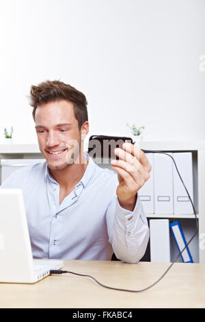 College Student machen die Datenübertragung von Handy auf Laptop-computer Stockfoto