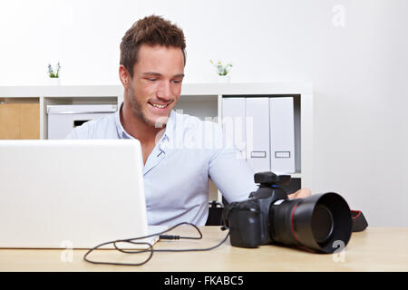 Glückliche Fotograf herunterladen von Fotos von Kamera auf Laptop-computer Stockfoto
