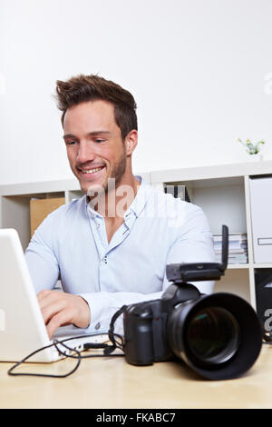 Professioneller Fotograf mit Kamera und Laptop-Computer im Büro Stockfoto