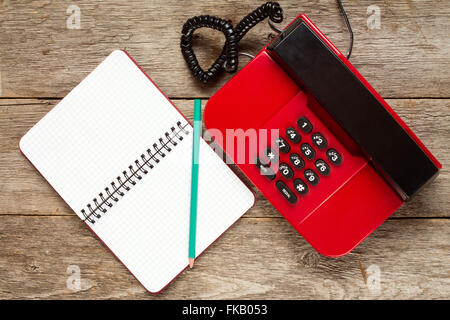 Vintage Telefon und leeren Notebook auf urigen Holzbrettern. Ansicht von oben. Stockfoto