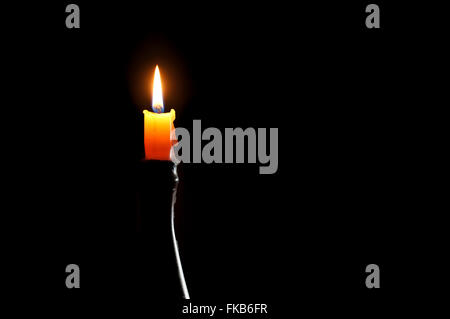 Einzelne Wachs Kerzenflamme brennt in der Dunkelheit. Stockfoto