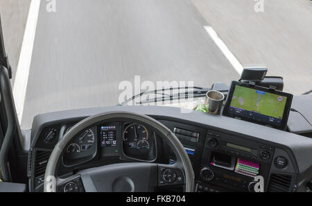 Blick von oben auf Armaturenbrett im Fahrerhaus des LKW während der Fahrt. Die Karte ist absichtlich etwas unscharf. Stockfoto