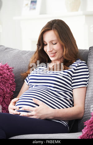 Schwangere Frau zu Hause auf Sofa entspannen Stockfoto