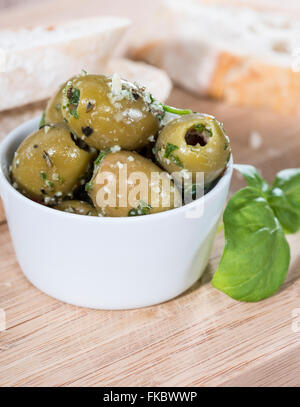 Portion grüne Oliven (Nahaufnahme) mit frischen Kräutern und Knoblauch Stockfoto