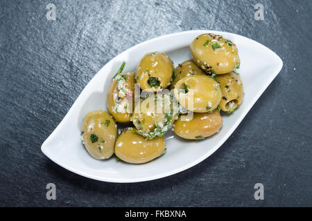 Portion eingelegte grüne Oliven mit Knoblauch und frischen Kräutern Stockfoto