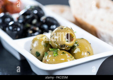 Gemischte Oliven (schwarz und grün sind) mit Knoblauch und frischen mediterranen Kräutern mariniert Stockfoto
