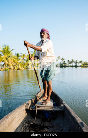 Anthony der Bootsmann Führung des Schiffes durch Keralas Backwaters in der Nähe von North Paravoor, Kerala, Indien Stockfoto