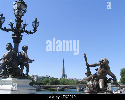 Bronze-Skulpturen von Putten auf Pont Alexandre III, mit dem Eiffelturm und Pont des Invalides. Stockfoto