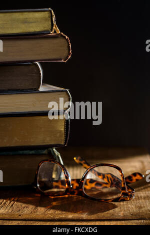 Brillen und Stapel Bücher auf Tisch Stockfoto