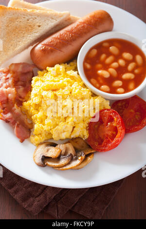 englisches Frühstück mit Rührei, Speck, Würstchen, Bohnen, Tomaten Stockfoto