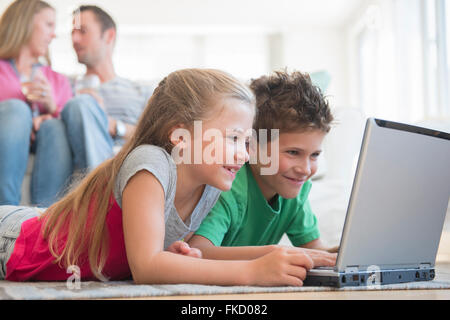 Jungen und Mädchen (6-7, 8-9) am Boden liegend und mit laptop Stockfoto