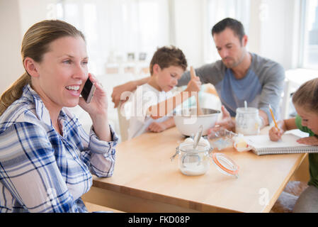 Familie mit zwei Kindern (6-7, 8-9) sitzen am Tisch Stockfoto