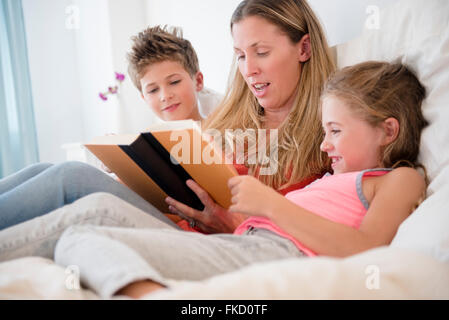 Mutter mit Tochter (6-7) und Sohn (8-9) lesen Stockfoto