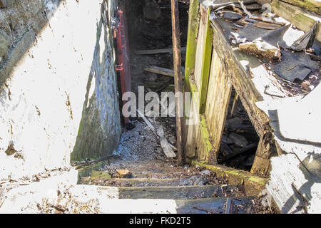 Stufen führen hinunter zu einem unteren Stockwerk in einer stillgelegten und verlassenen Fabrik Stockfoto