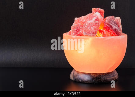 Himalaya rosa Salzlampe als eine Schale auf einem schwarzen Tisch mit Vintage strukturierte dunkelgrauen Hintergrund geschnitzt eingeschaltet. Stockfoto