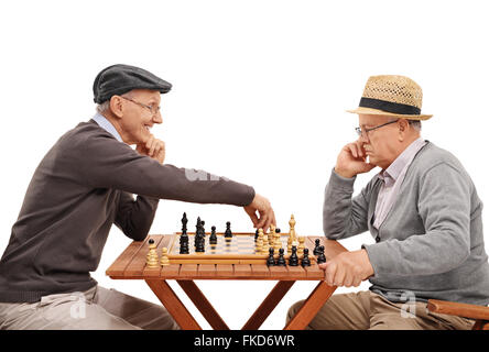 Studioaufnahme von zwei alten Freunden eine Partie Schach zu spielen, an einem Holztisch isoliert auf weißem Hintergrund Stockfoto
