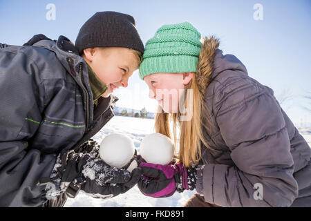 Kinder (8-9, 10-11) Holding Schneebälle und berührende Stirn Stockfoto