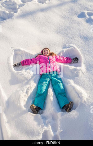 Mädchen (10-11) in rosa Jacke Schneeengel machen Stockfoto