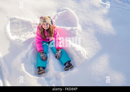 Mädchen (10-11) in rosa Jacke sitzen im Schnee Stockfoto