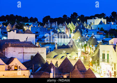 Trulli Häuser entlang der beleuchteten Street unter blauem Himmel Stockfoto