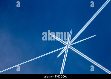 Vapor Trails von Flugzeugen im blauen Himmel gekreuzt Stockfoto