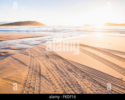 Reifenspuren am Strand bei Sonnenuntergang Stockfoto