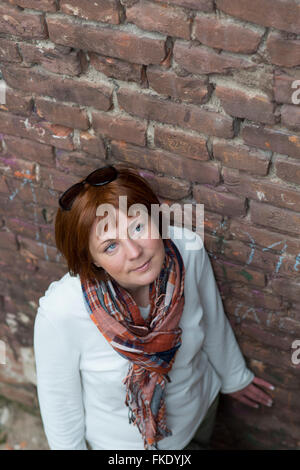 Frau in der Nähe von alten, gemauerten Wand nachschlagen Stockfoto