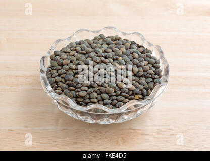 Eine Portion grüne Linsen in eine kleine Glasschüssel auf einem Holztisch. Stockfoto