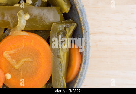 Enge Draufsicht einer Portion Dose geschnittene Jalapeño Paprika mit Karotten in eine alte Schüssel oben auf einer hölzernen Tischplatte. Stockfoto