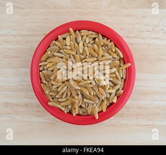 Draufsicht auf eine kleine Schüssel gefüllt mit Kamut Khorasan Weizen auf einem Holztisch mit natürlichem Licht beleuchtet. Stockfoto