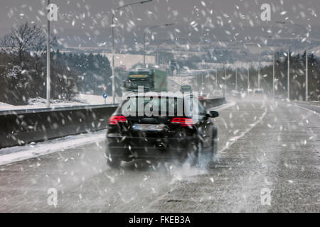 Autos fahren auf rutschigen Autobahn bei starkem Schneefall verursacht Dusche winterlichen gefährlich nassen Straßenverhältnissen im Winter / Frühjahr Stockfoto
