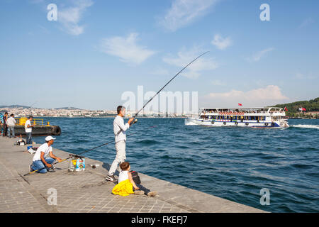 Männer Angeln am Kai und Personenfähre vorbei, den Bosporus, Istanbul, Türkei Stockfoto